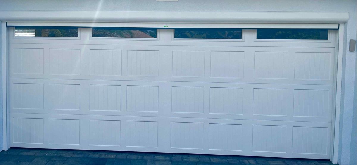 A new white sectional garage door on a stucco home