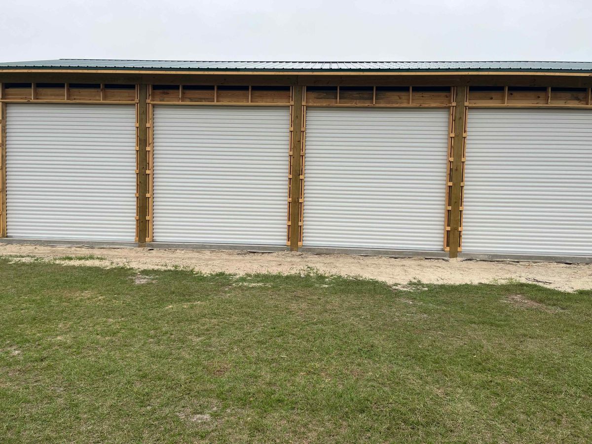 A metal outbuilding with four new white roll-up doors