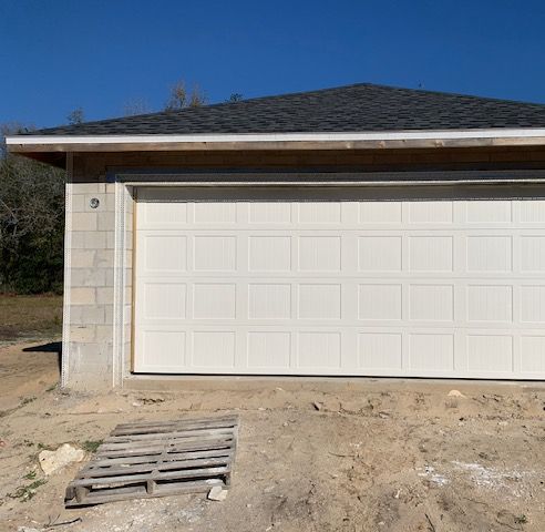 A new white garage door hung on a block garage under construction