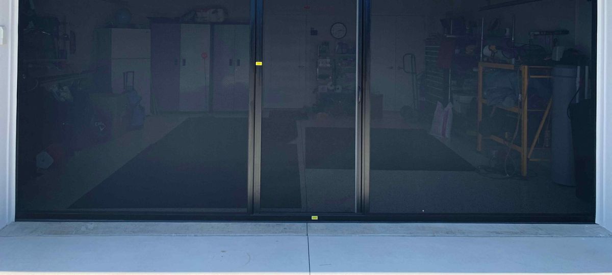 A retractable screen lowered across an open garage doorway