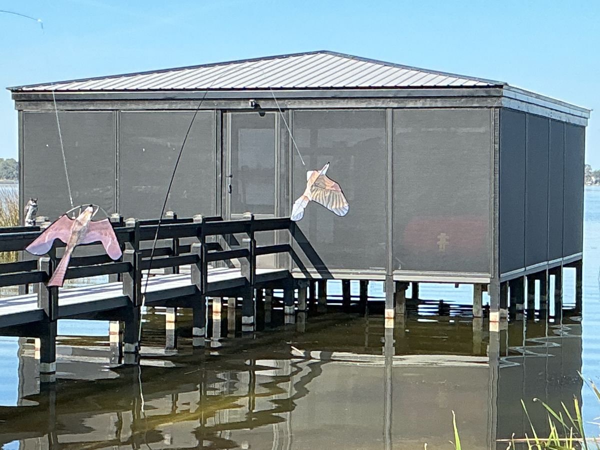 A screened dock house with a flamingo decoration on the walkway