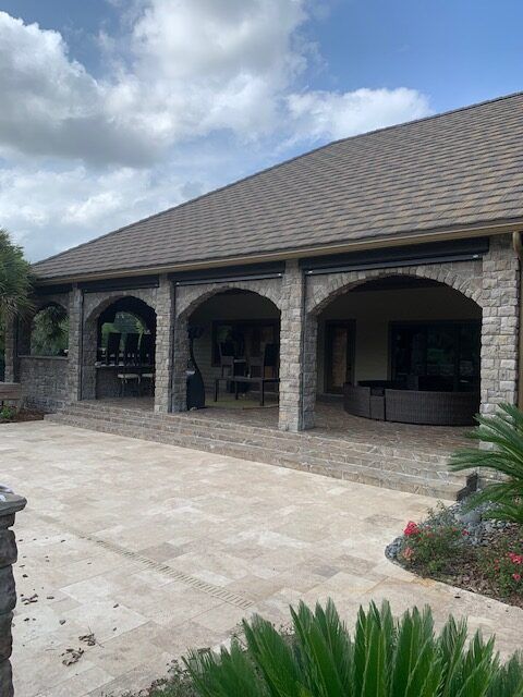A stone-arched lanai with motorized screens seen from the lawn