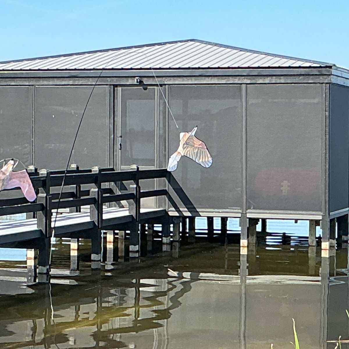A screened dock house with a flamingo decoration on the lake