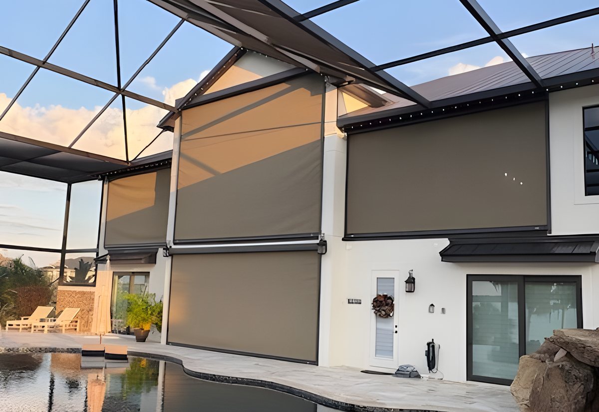 Motorized screens lowered across a two-story pool lanai inside a screen cage at dusk, reflected in the pool